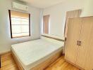 Minimalist bedroom with wooden floor, double bed, wardrobe, and air conditioning