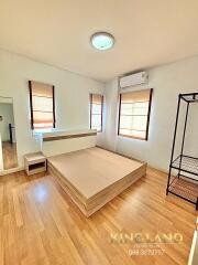 Bright and spacious bedroom with wooden floors, minimalist bed frame, and large windows.