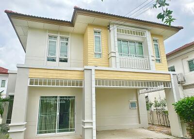 Two-story house with a carport and lush greenery