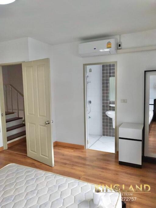 Bedroom with an attached bathroom and open door showing staircase.