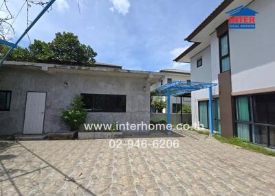 Exterior view of the property showing two buildings and a paved courtyard