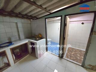 Small kitchen area with tiled backsplash and sink, adjacent to bathroom