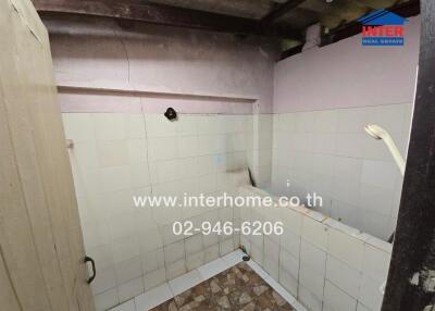 Small, partially tiled bathroom with visible plumbing and a bath