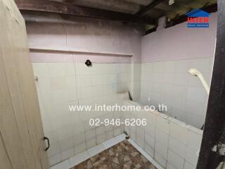 Small, partially tiled bathroom with visible plumbing and a bath