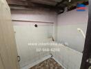 Small, partially tiled bathroom with visible plumbing and a bath