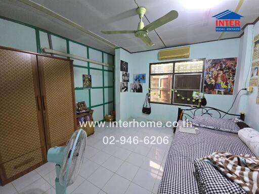 Interhome real estate bedroom with bed, wardrobe, window, fan, and wall decorations.