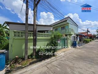 Exterior view of a residential building with green walls and a green fence