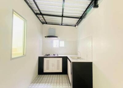 Modern minimalist kitchen with white walls, hexagonal patterned floor tiles, black countertop and cabinets, small window, and exhaust hood.