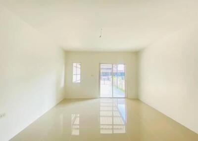 View of an empty living room with a window and glass door leading to an outdoor area