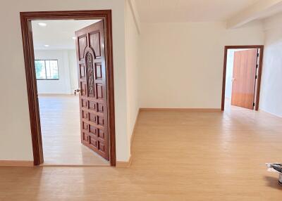 View of a bright, empty room with multiple doorways and wooden flooring