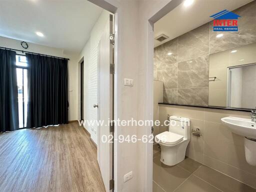 View of a bathroom and an adjacent room with wooden flooring