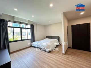 Modern bedroom with wooden flooring, large window, and double bed