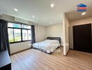 Modern bedroom with wooden flooring, large window, and double bed