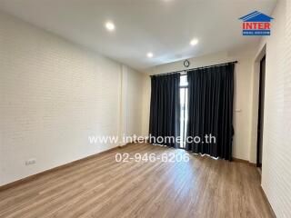 Spacious living room with wooden flooring and large windows featuring black curtains