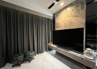 Living room with marble accent wall, large TV, and modern furniture