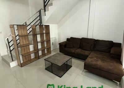 Modern living room with staircase and brown sofa