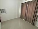 Empty bedroom with curtains and mounted air conditioner