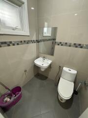 Modern bathroom with sink, mirror, toilet, and cleaning supplies