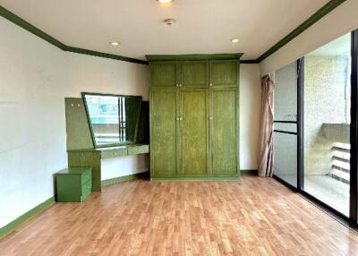 Spacious bedroom with green accents and wooden flooring