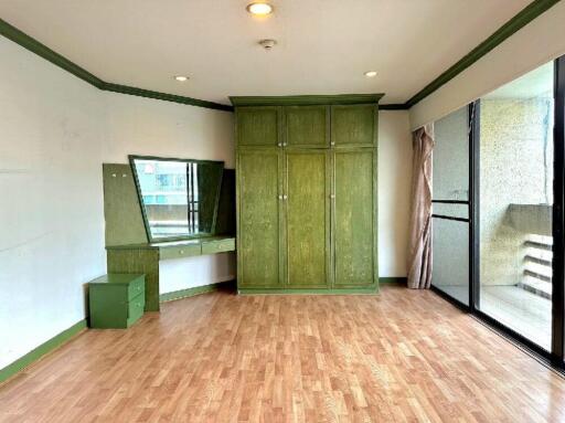 Spacious bedroom with green accents and wooden flooring