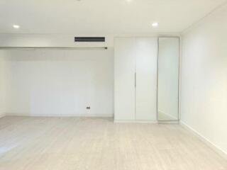 Spacious empty bedroom with built-in wardrobe and large mirror