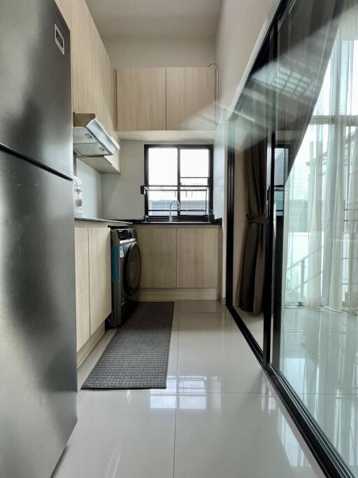 Modern kitchen with stainless steel refrigerator, washing machine, and large window