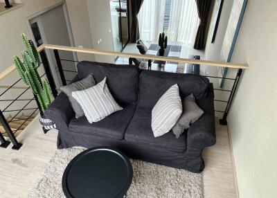 Loft view of a living room with a couch, coffee table, and large window