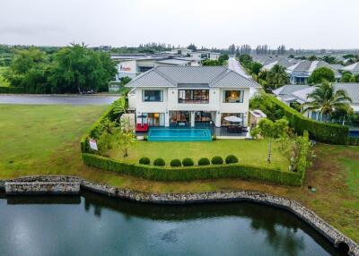 Exterior view of a luxury house with a swimming pool and garden in a suburban setting