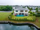 Exterior view of a luxury house with a swimming pool and garden in a suburban setting