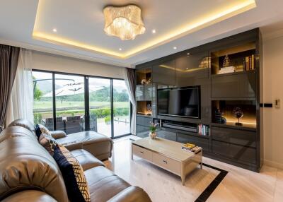 Modern living room with leather sofas, large TV, and sliding glass doors to outdoor patio.