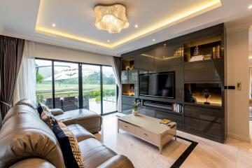 Modern living room with leather sofas, large TV, and sliding glass doors to outdoor patio.