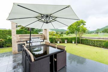 Outdoor seating area with dining table, umbrella, and BBQ grill