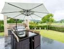 Outdoor seating area with dining table, umbrella, and BBQ grill