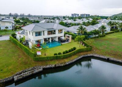 Aerial view of a modern house with a swimming pool and a lake