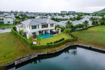 Aerial view of a modern house with a swimming pool and a lake