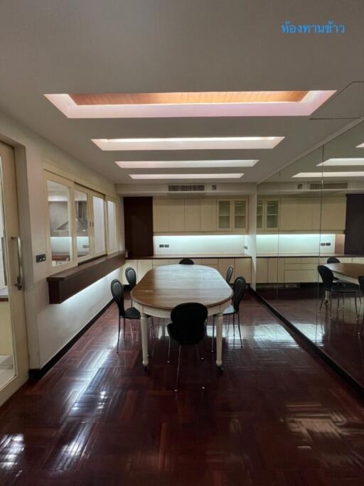 Dining room with wooden table, chairs, mirror wall, and modern lighting