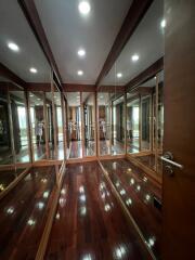 Spacious walk-in closet with full-length mirrors and wooden flooring