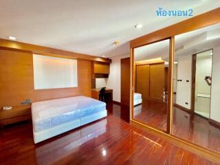 Spacious bedroom with wooden flooring and large mirror closet