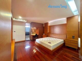 Spacious bedroom with wooden flooring, a large bed, and an attached bathroom