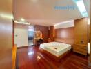 Spacious bedroom with wooden flooring, a large bed, and an attached bathroom