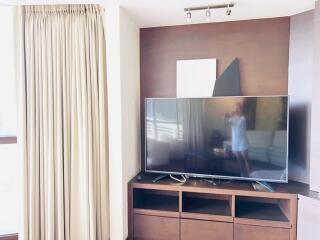 Living room with large flat-screen TV and wooden entertainment unit