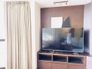 Living room with large flat-screen TV and wooden entertainment unit