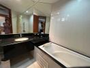 Modern bathroom with large mirror, black countertop and bathtub