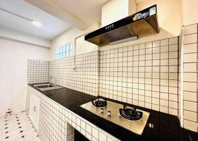 Modern kitchen with tiled backsplash and countertops, gas stovetop, and sink.