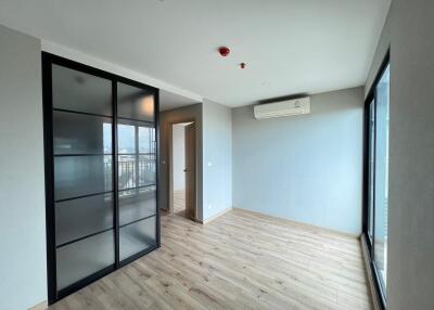 Spacious living room with sliding glass door, wooden flooring, and a large window