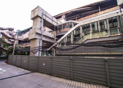 Exterior view of a modern building with exposed utility lines and adjacent structures.