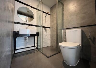 Modern bathroom with round mirror, sink, shower, and toilet