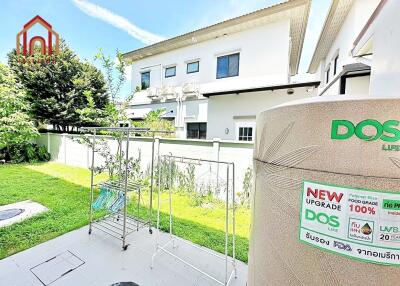 Backyard with drying racks, greenery, and house exterior