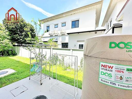 Backyard with drying racks, greenery, and house exterior