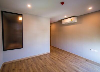 Empty bedroom with wooden floor and air conditioning